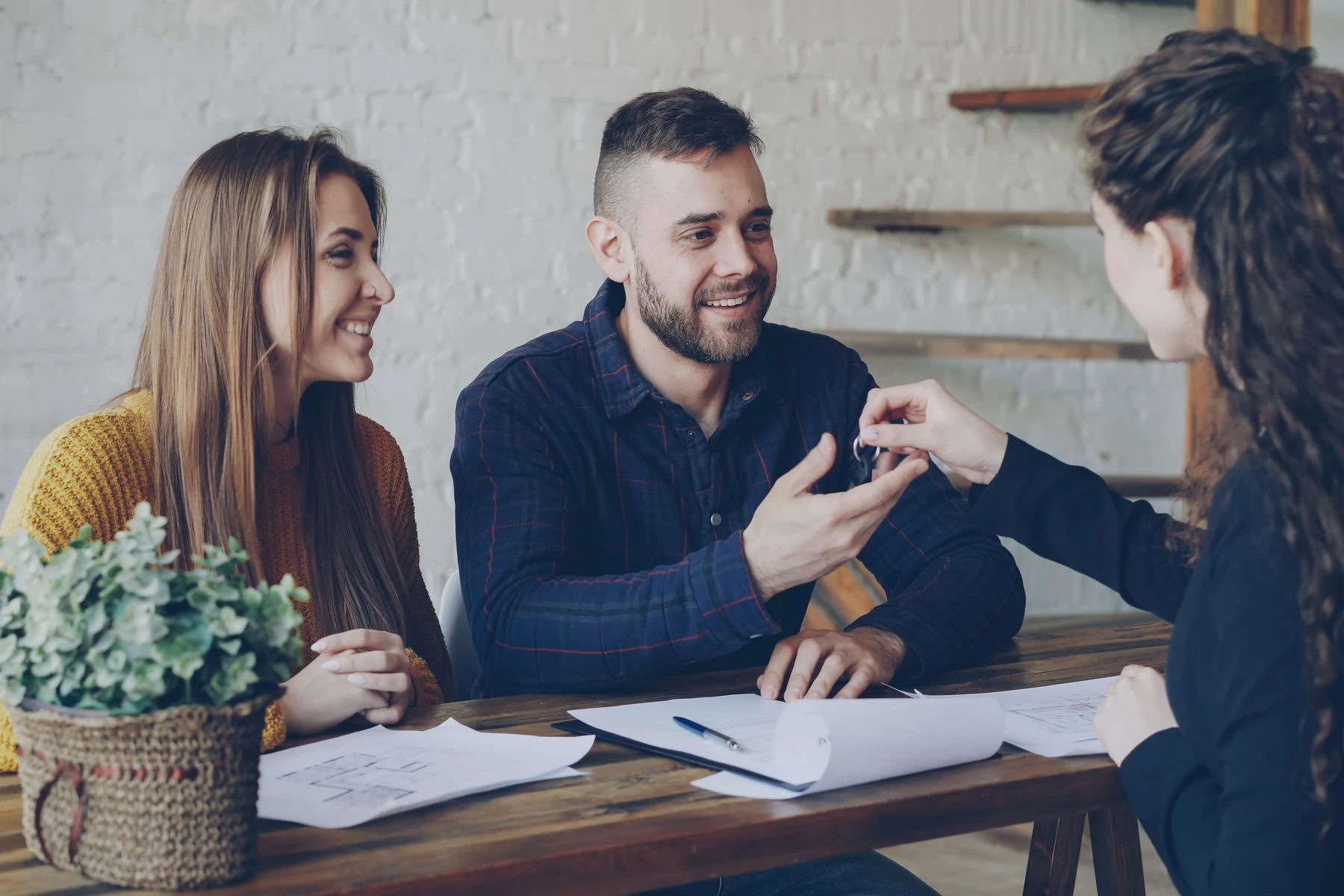 A smiling couple receiving house keys from a real estate agent.